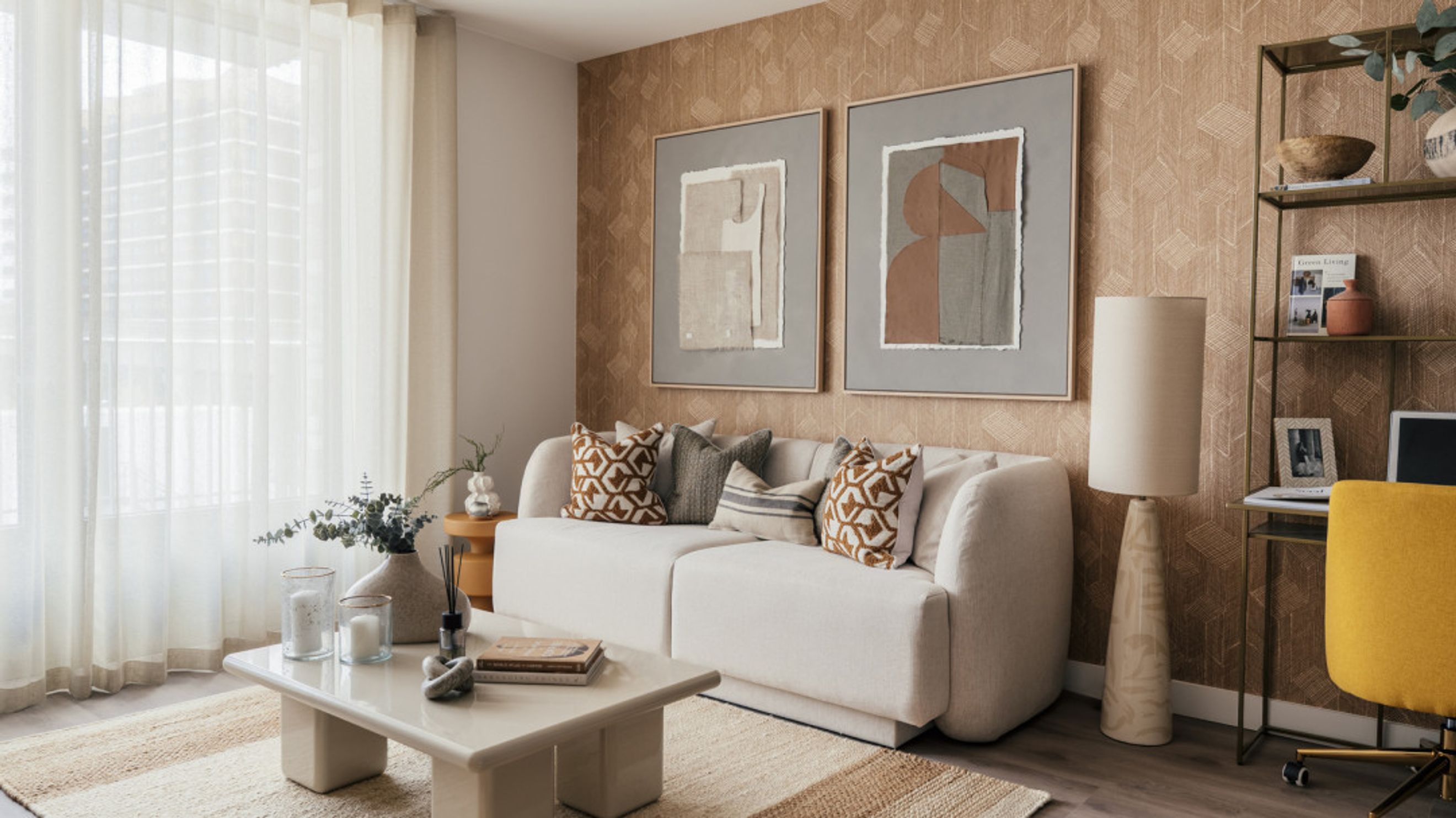 A living room with a white sofa, coffee table, floor lamp, and artwork.