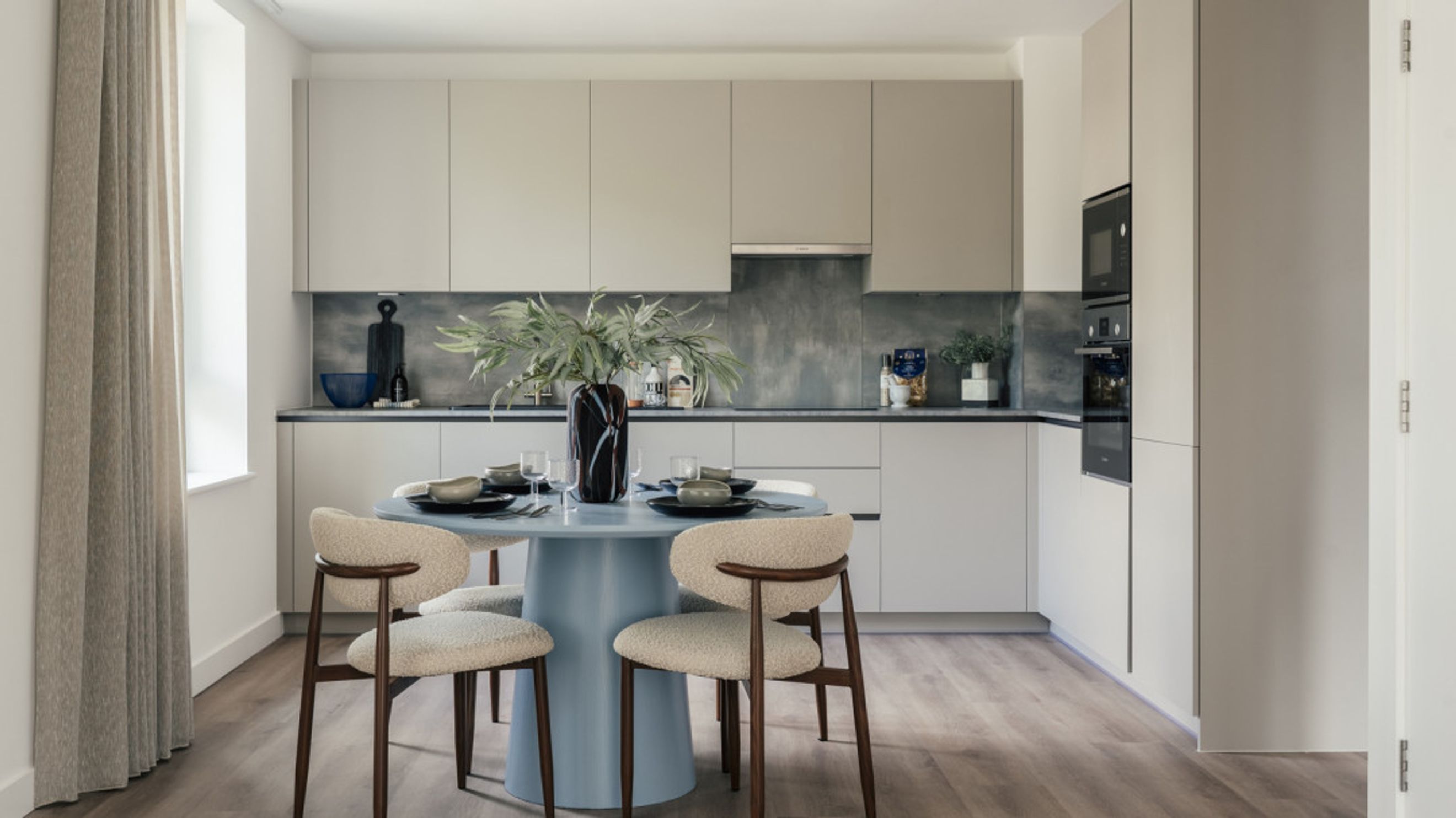 A dining area and kitchen with a round table, chairs, and modern cabinetry.