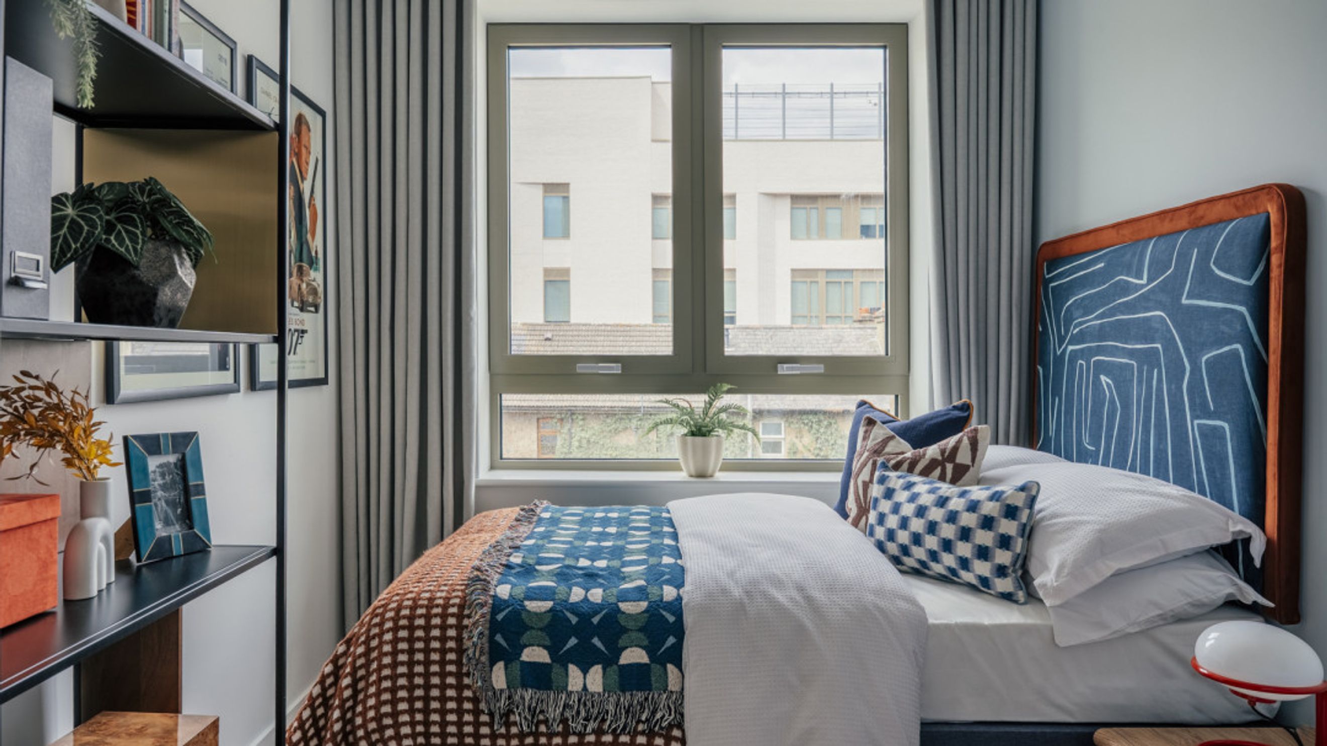 A bedroom with a bed, pillows, a throw blanket, and a window.