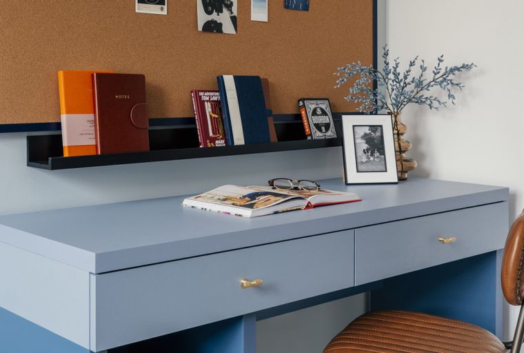 A blue desk with books, glasses, and a framed photo on top.