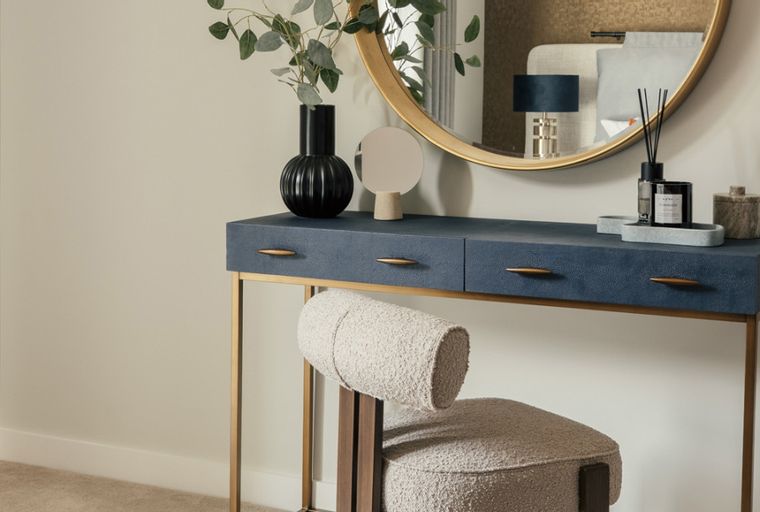 A vanity table with a mirror and a stool.