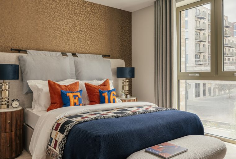 A bedroom with a bed, pillows, a nightstand, and a window.
