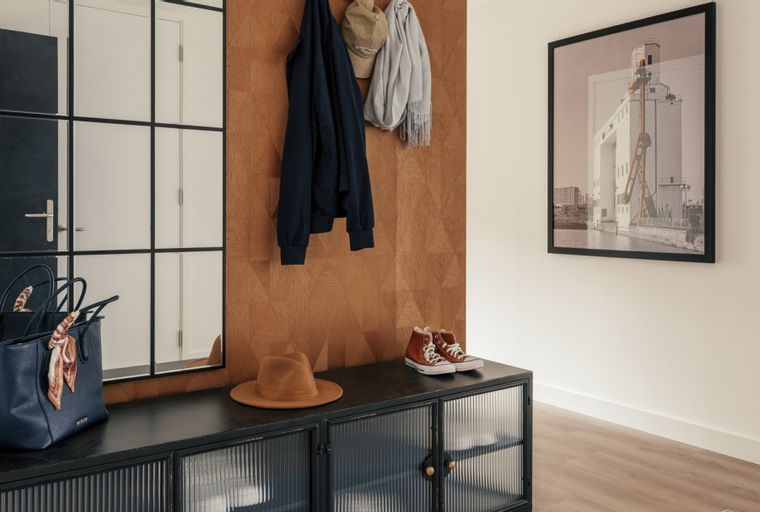 A hallway with a console table, mirror, and artwork.