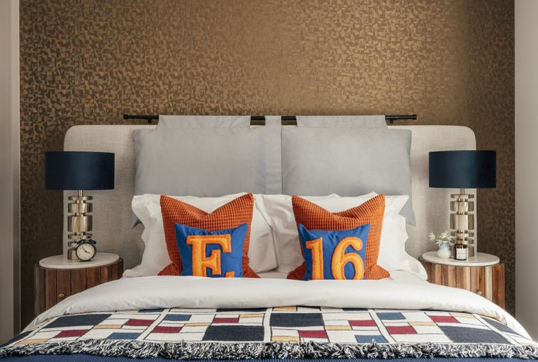 A bedroom with a bed, pillows, and bedside lamps.