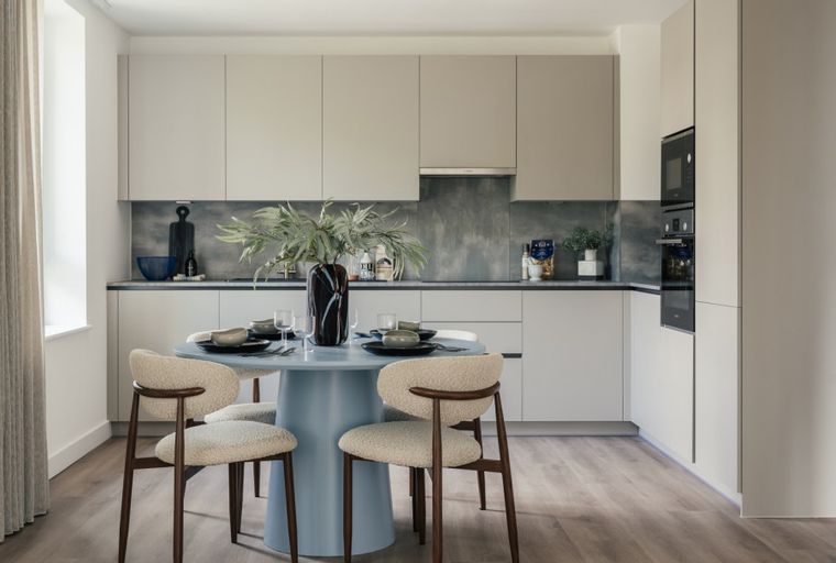 A dining area and kitchen with a round table, chairs, and modern cabinetry.