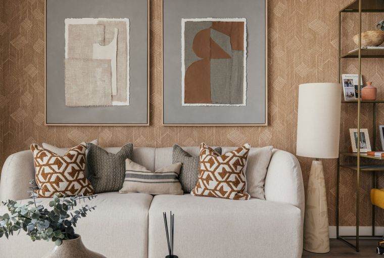 A living room with a sofa, pillows, artwork, and a floor lamp.