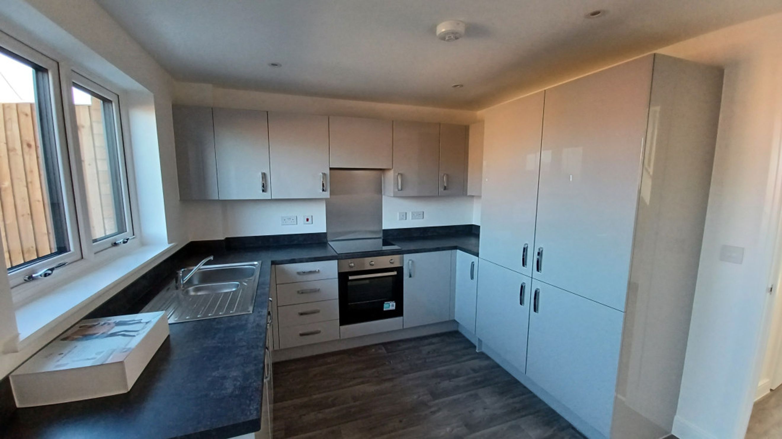 A modern kitchen with white cabinets, a dark countertop, and an oven.
