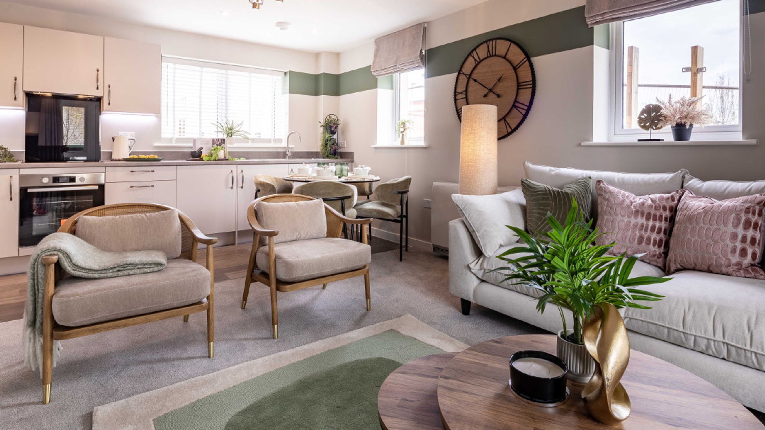 A living room and kitchen area with a sofa, chairs, dining table, and kitchen cabinets.