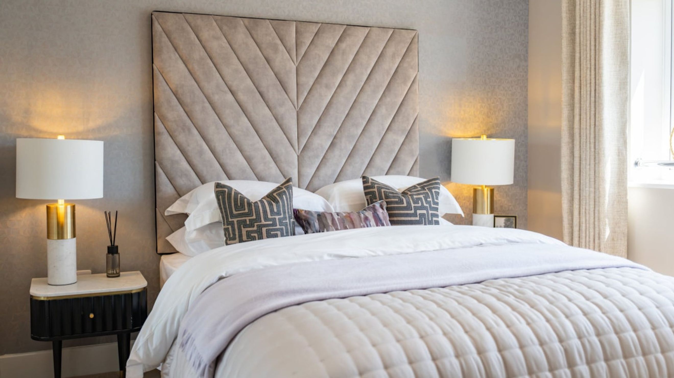 A bedroom with a bed, pillows, and bedside lamps.