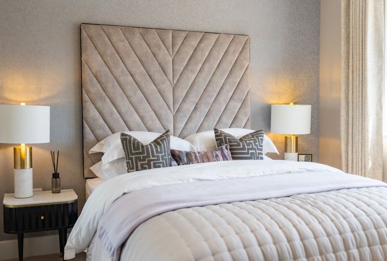 A bedroom with a bed, headboard, pillows, and bedside lamps.