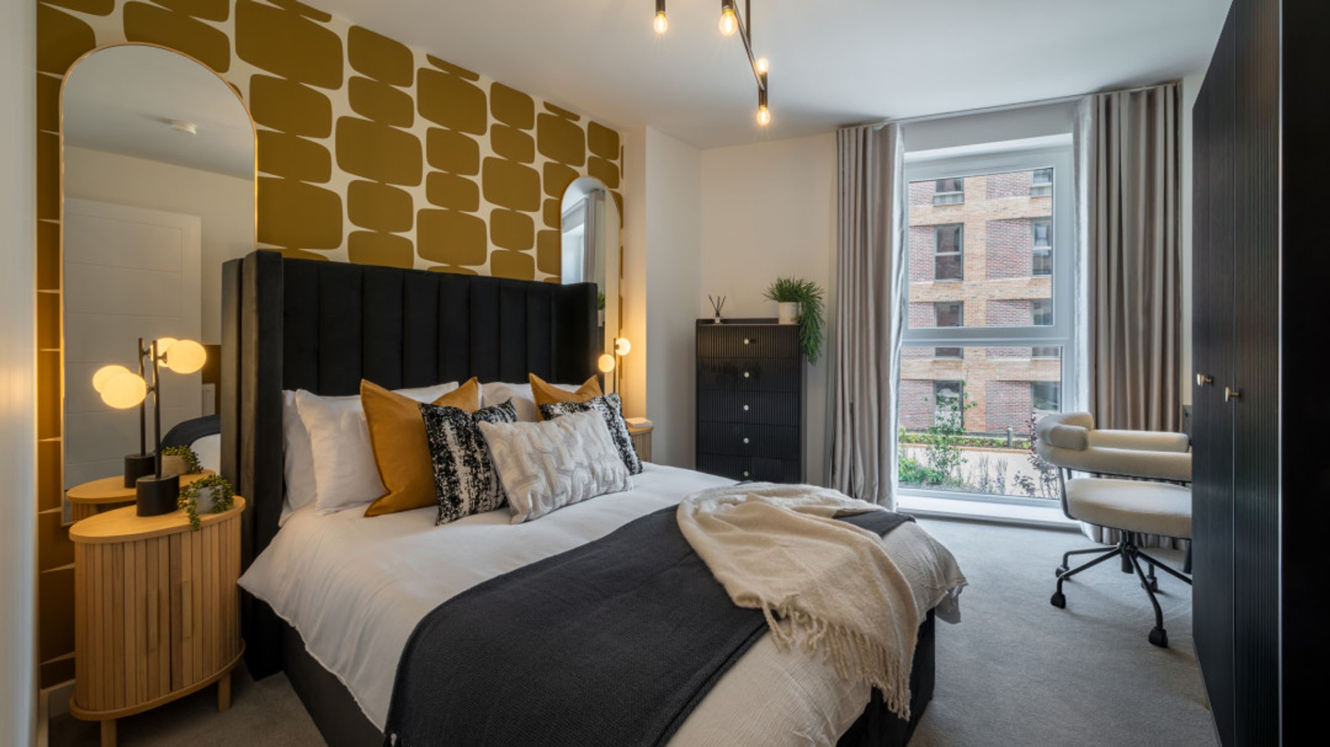 A bedroom with a bed, pillows, a dresser, a mirror, and a window.
