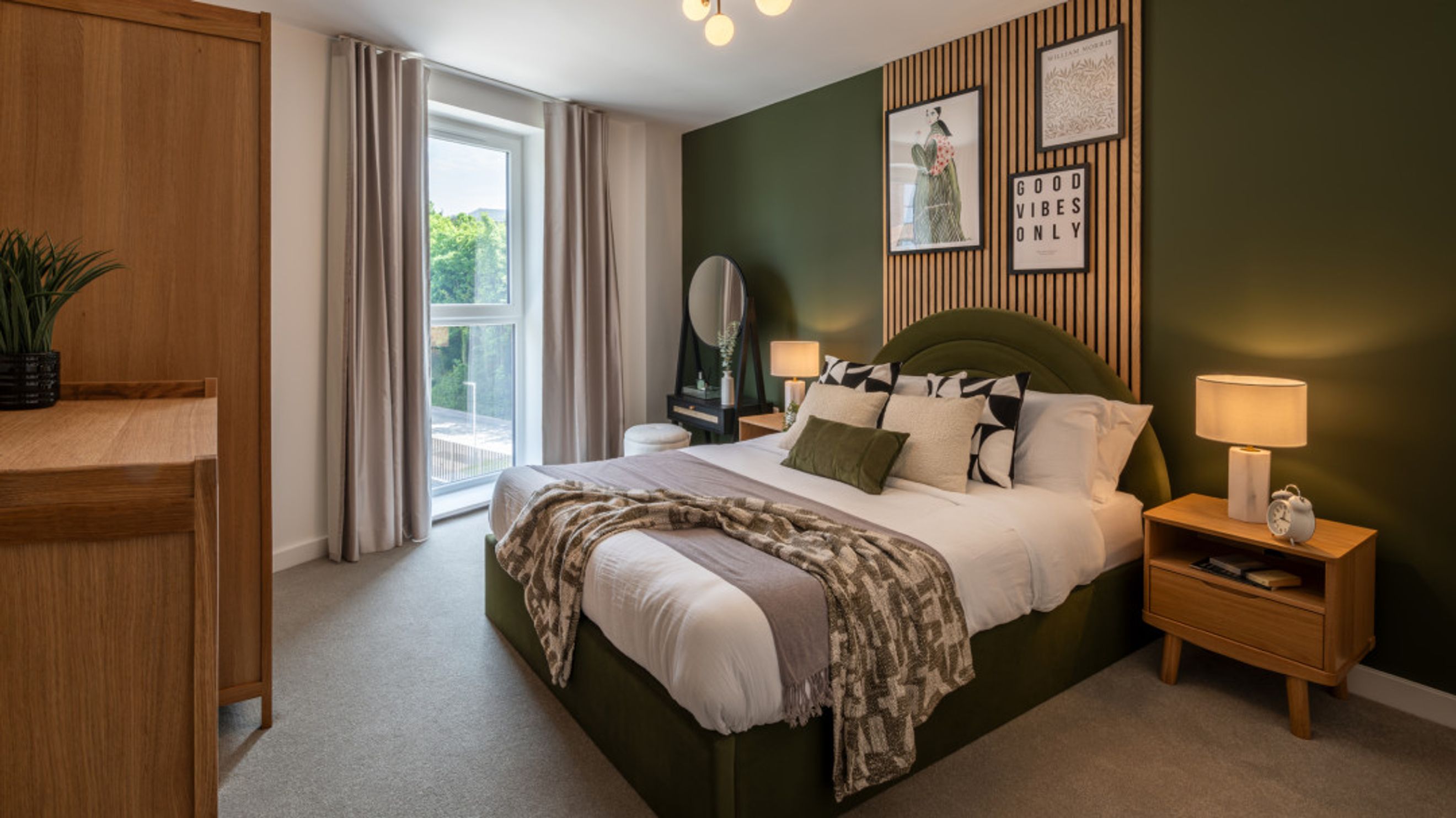 A bedroom with a bed, bedside tables, a dressing table, and a window.