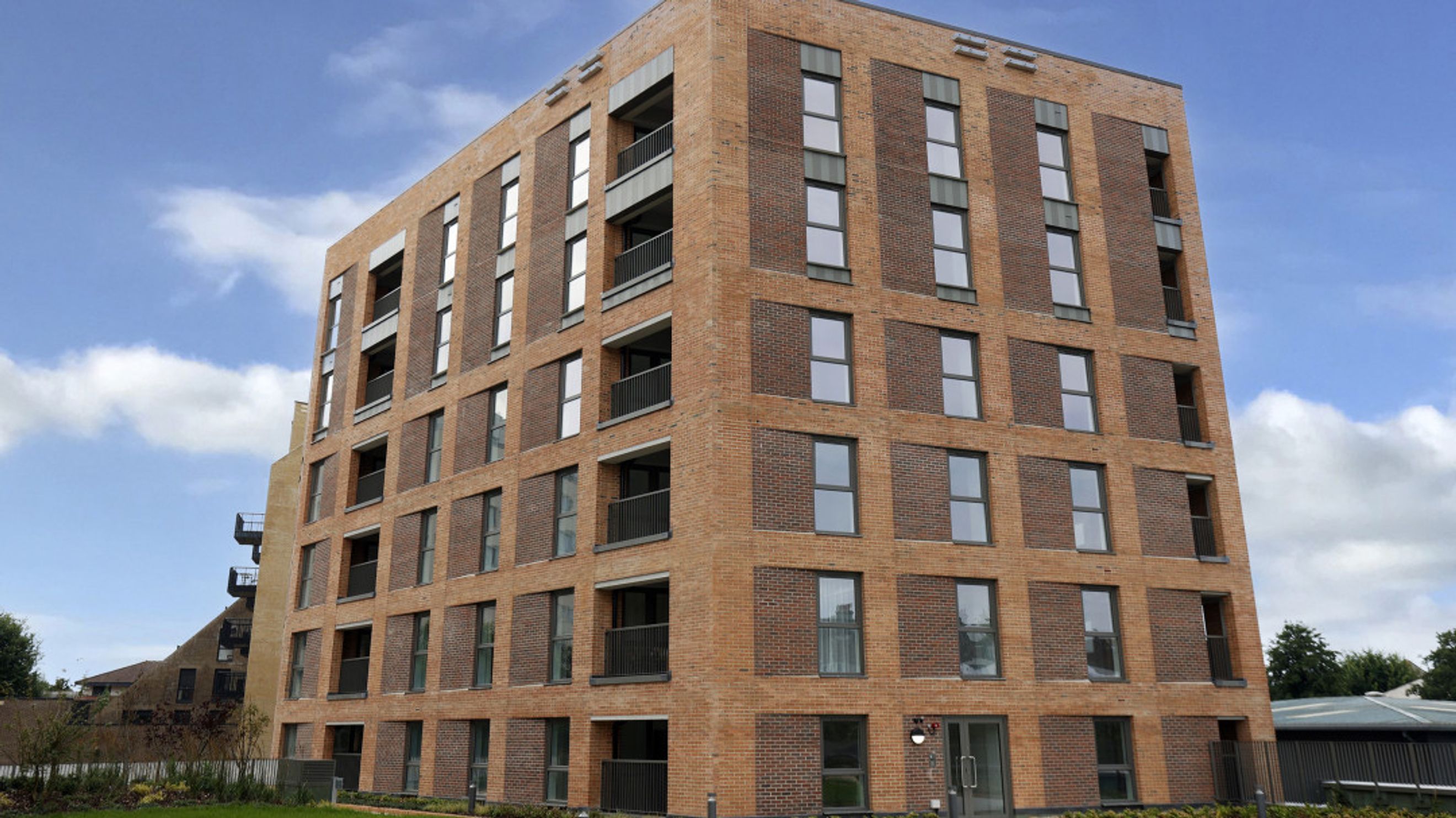 A modern brick apartment building with multiple floors and many windows.