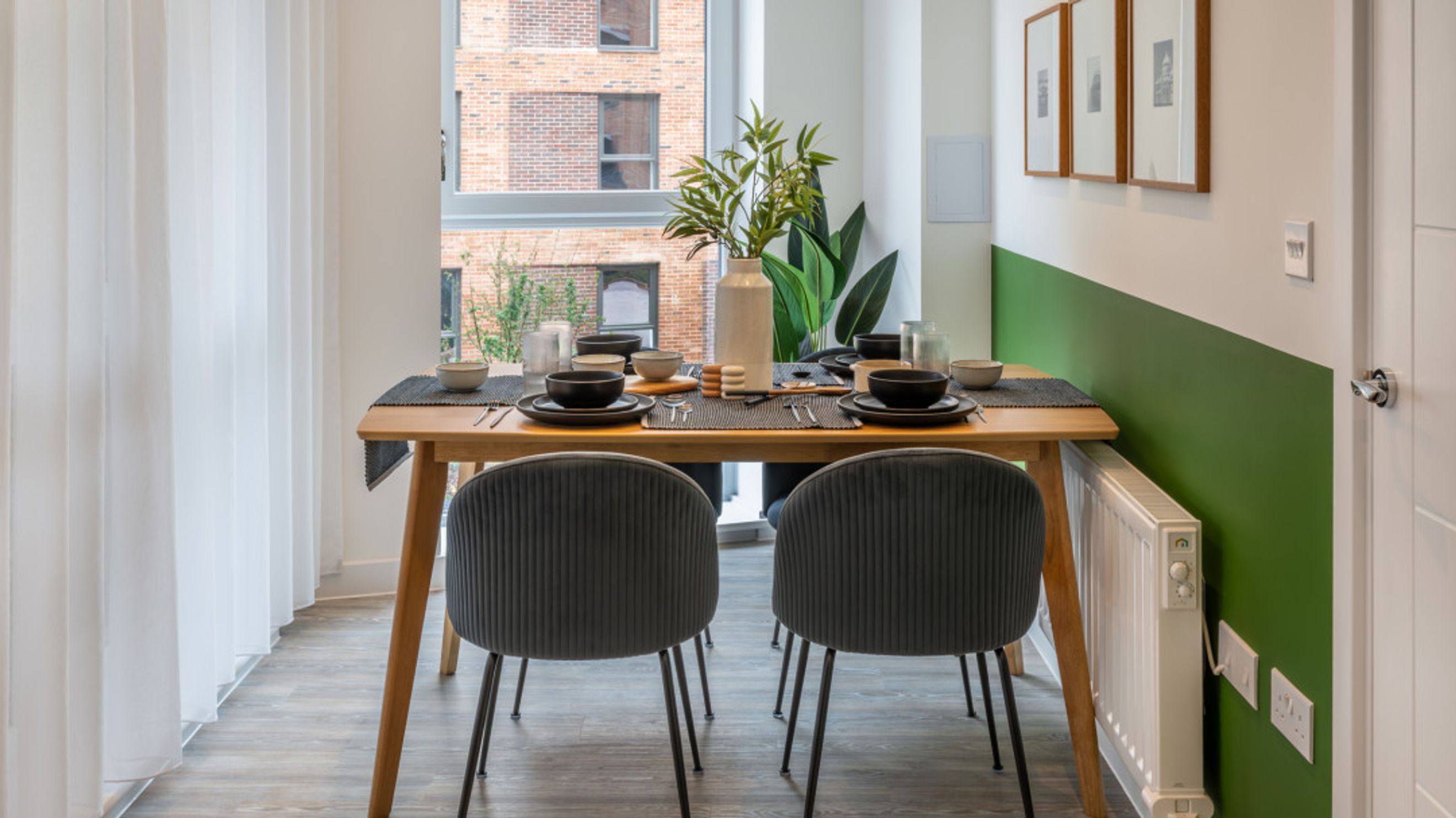 A dining table set for four with two chairs in front of a window.