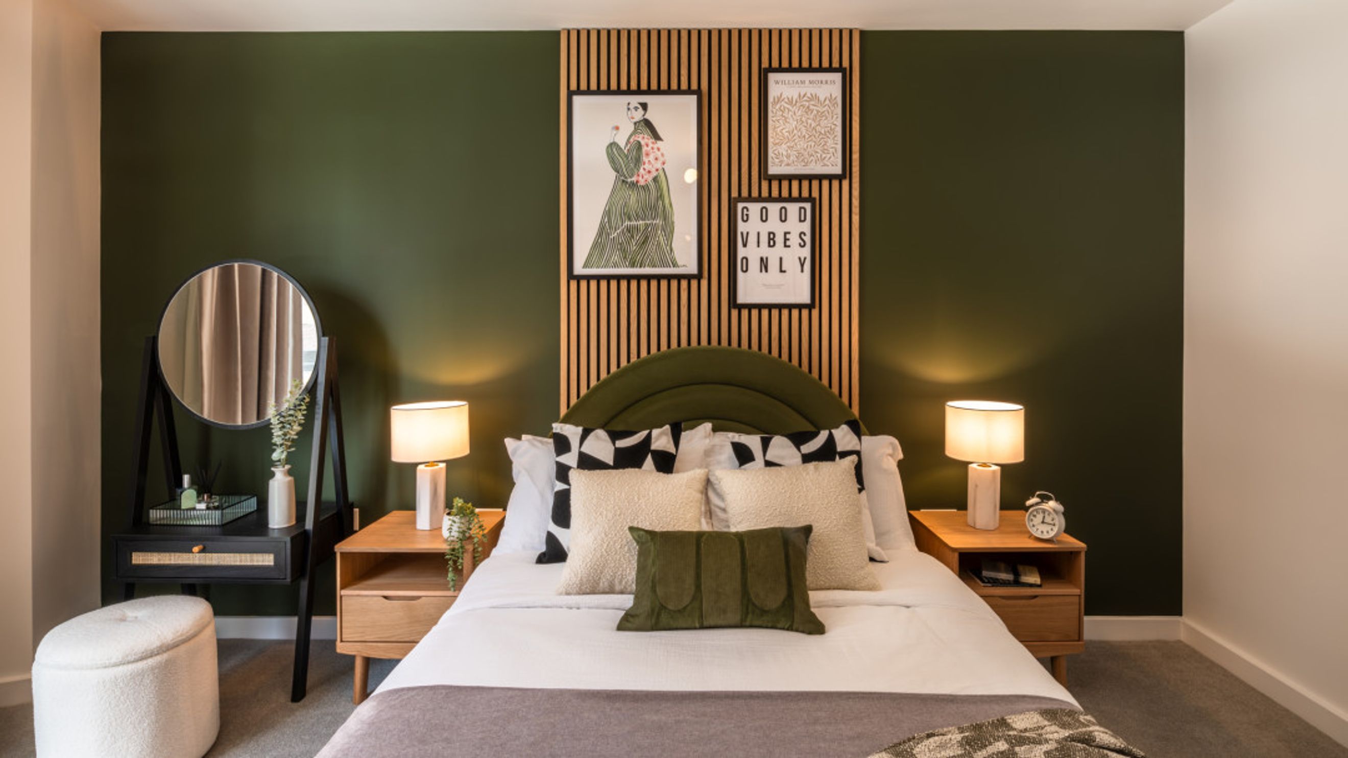 A bedroom with a bed, bedside tables, lamps, and artwork on a wooden slat wall.