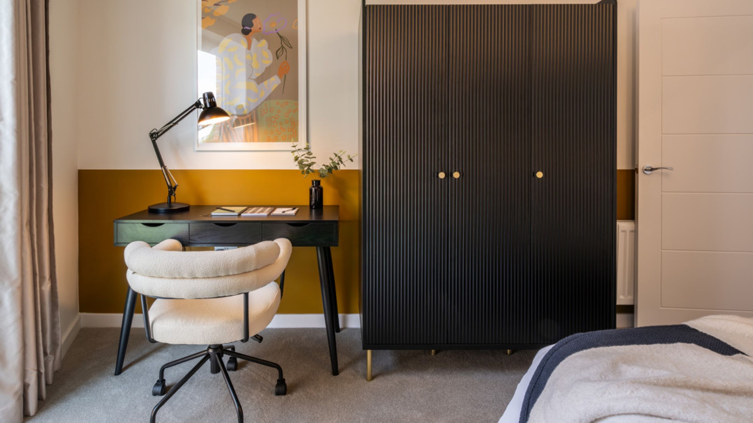 A bedroom with a desk, chair, and wardrobe.