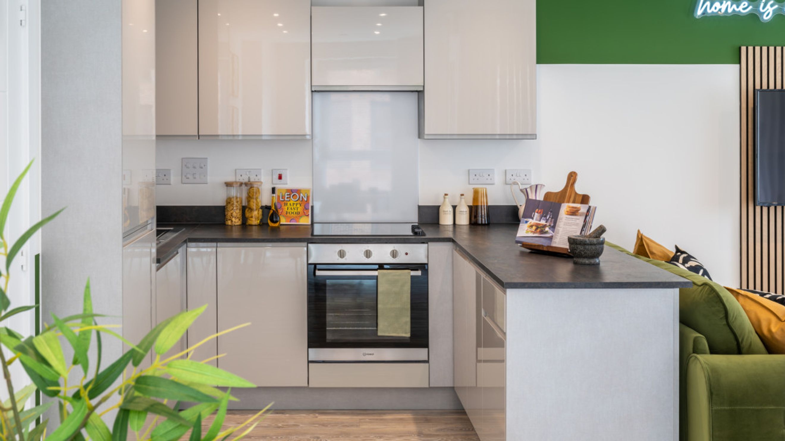A modern kitchen with sleek cabinets, a dark countertop, and an oven.