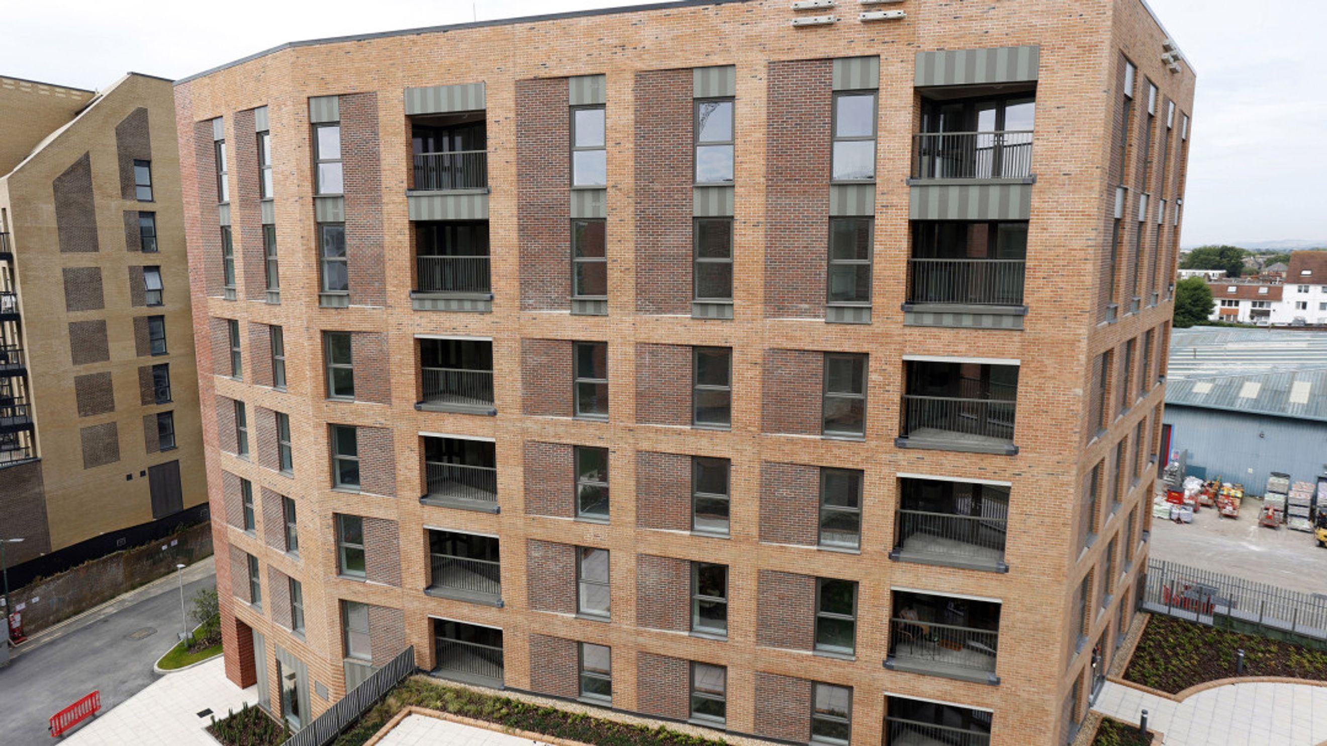 A modern brick apartment building with multiple balconies and windows.