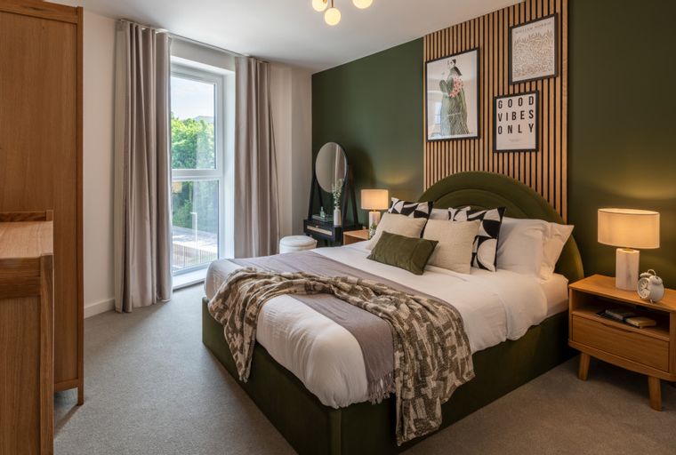 A bedroom with a bed, bedside tables, a dressing table, and a window.