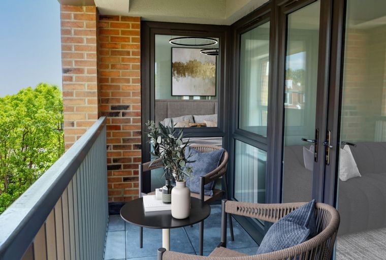 A balcony with two chairs, a table, and a view of trees.