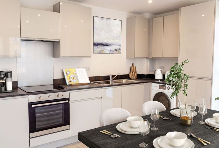 A kitchen and dining area with a stove, sink, cabinets, and a dining table set with plates and glasses.