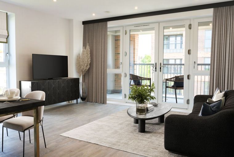 A living room with a sofa, coffee table, dining table, chairs, and a television.