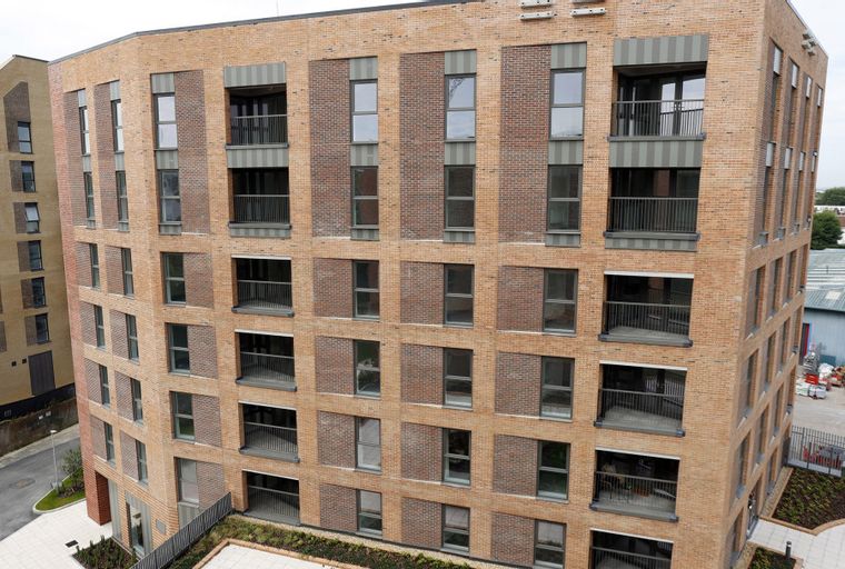 A modern brick apartment building with multiple balconies and windows.