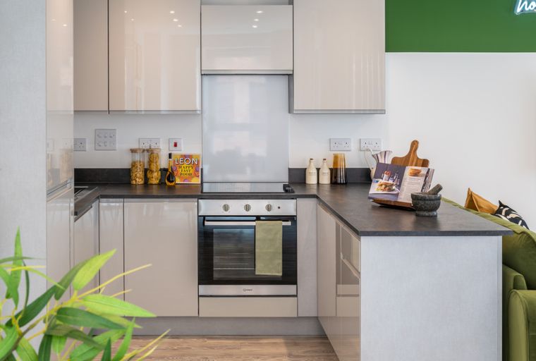 A modern kitchen with sleek cabinets, a dark countertop, and an oven.
