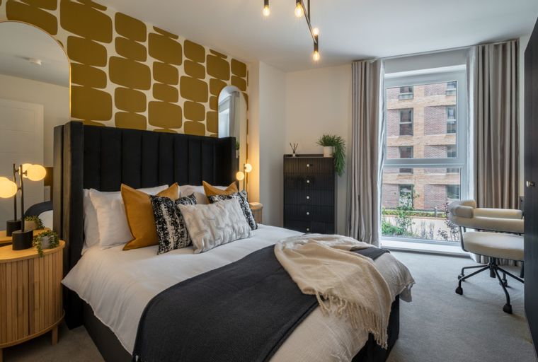 A bedroom with a bed, pillows, a dresser, a mirror, and a window.