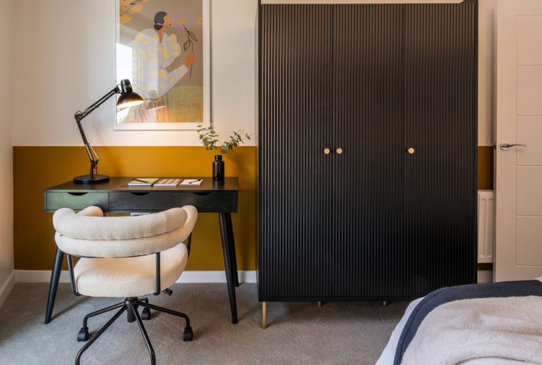 A bedroom with a desk, chair, and wardrobe.