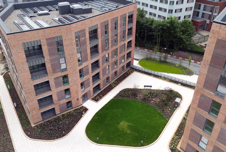 A view of modern brick apartment buildings with landscaped courtyards and walkways.