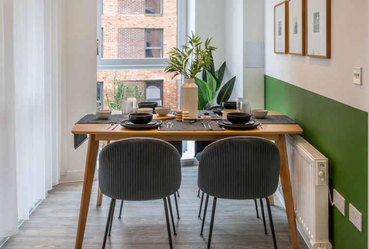 A dining table set for four with two chairs in front of a window.