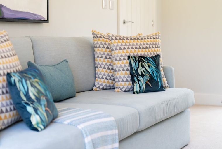 A light blue sectional sofa with decorative throw pillows and a throw blanket.