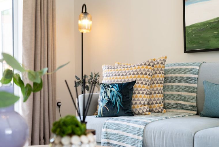 A living room with a sofa, pillows, a throw blanket, and a floor lamp.