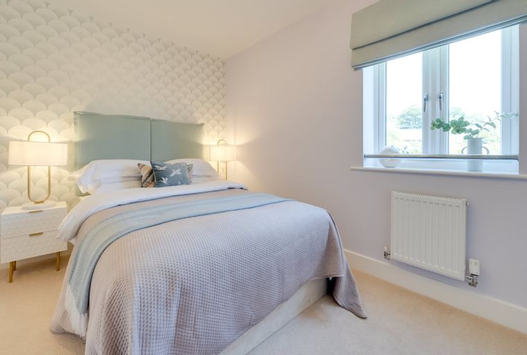 A bedroom with a bed, bedside tables, lamps, and a window.