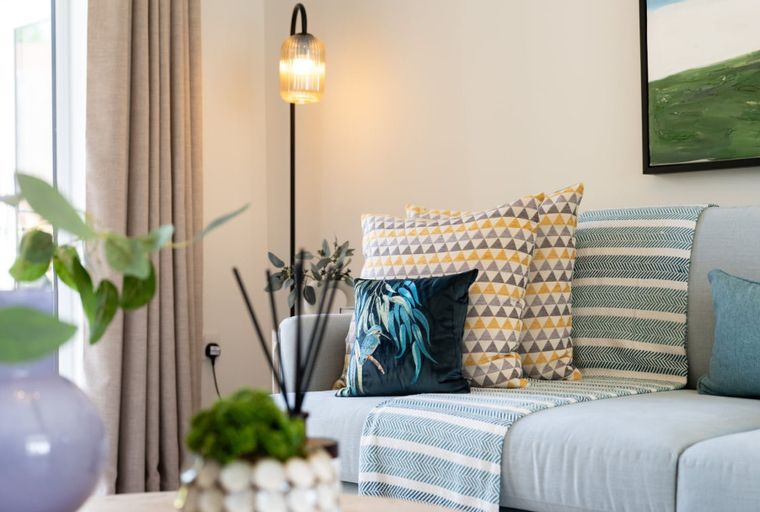 A light blue sofa with decorative pillows and a blanket.