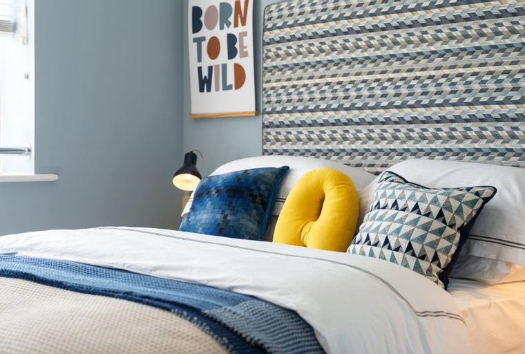 A bedroom with a bed, pillows, and a headboard.