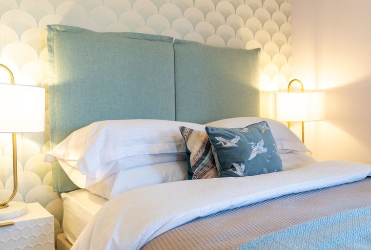 A bedroom with a bed, headboard, pillows, and bedside lamps.
