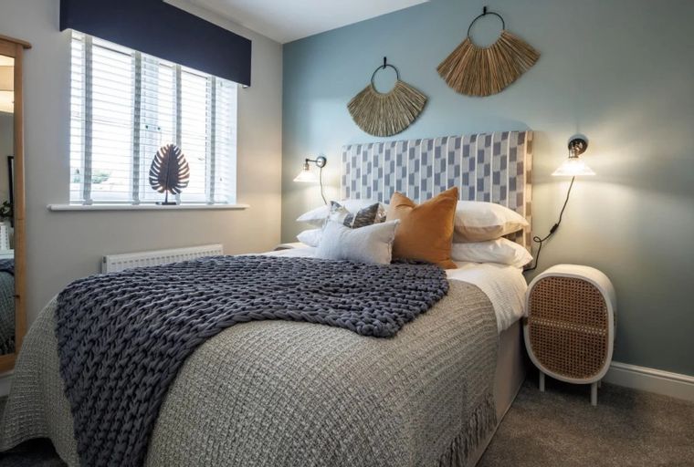 A bedroom with a bed, pillows, a throw blanket, wall decor, and a mirror.