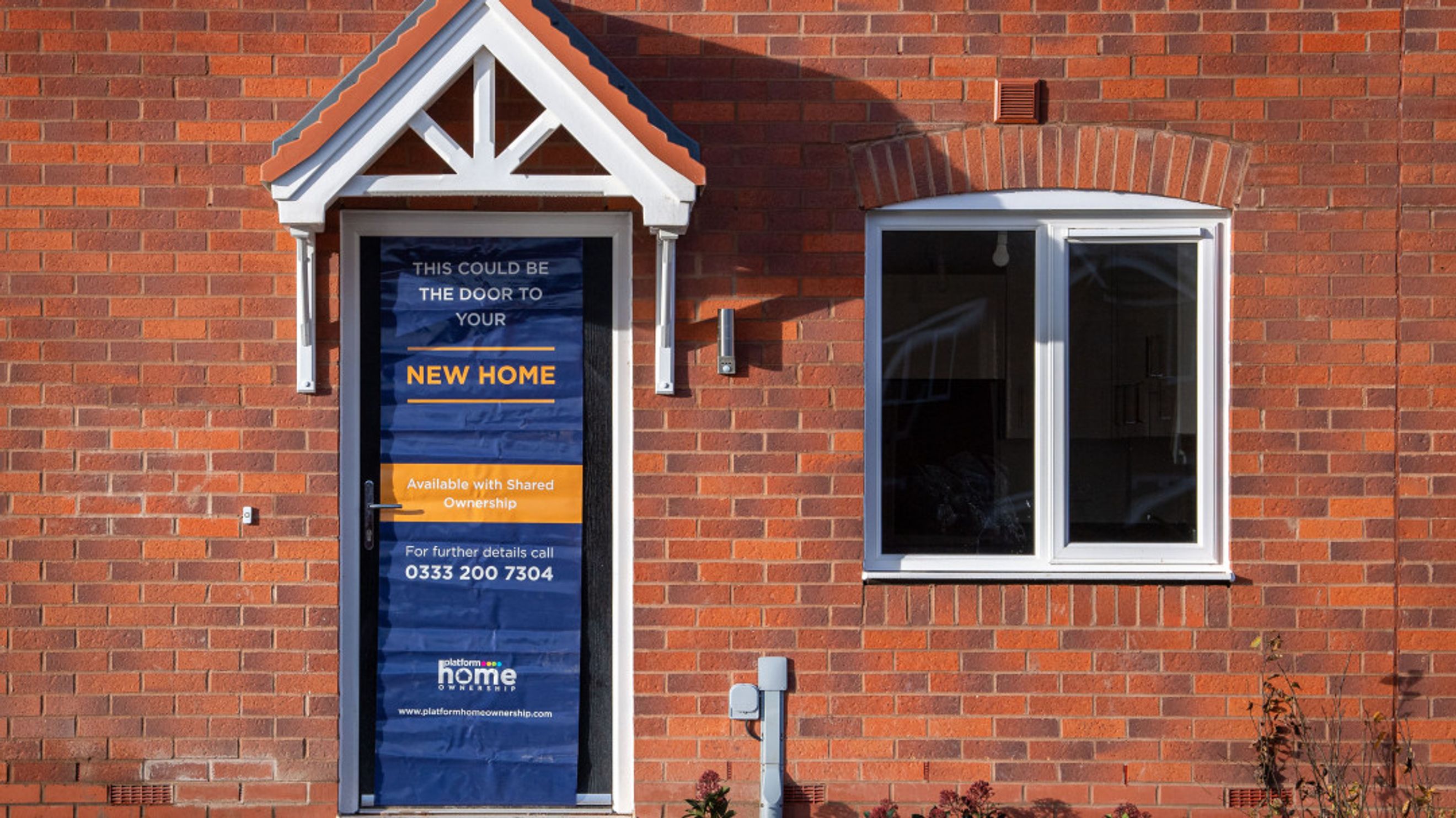 A front door with a sign advertising a new home available with shared ownership.