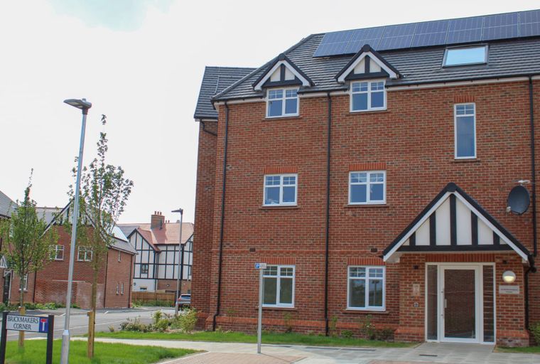 A brick apartment building with solar panels on the roof and multiple windows.