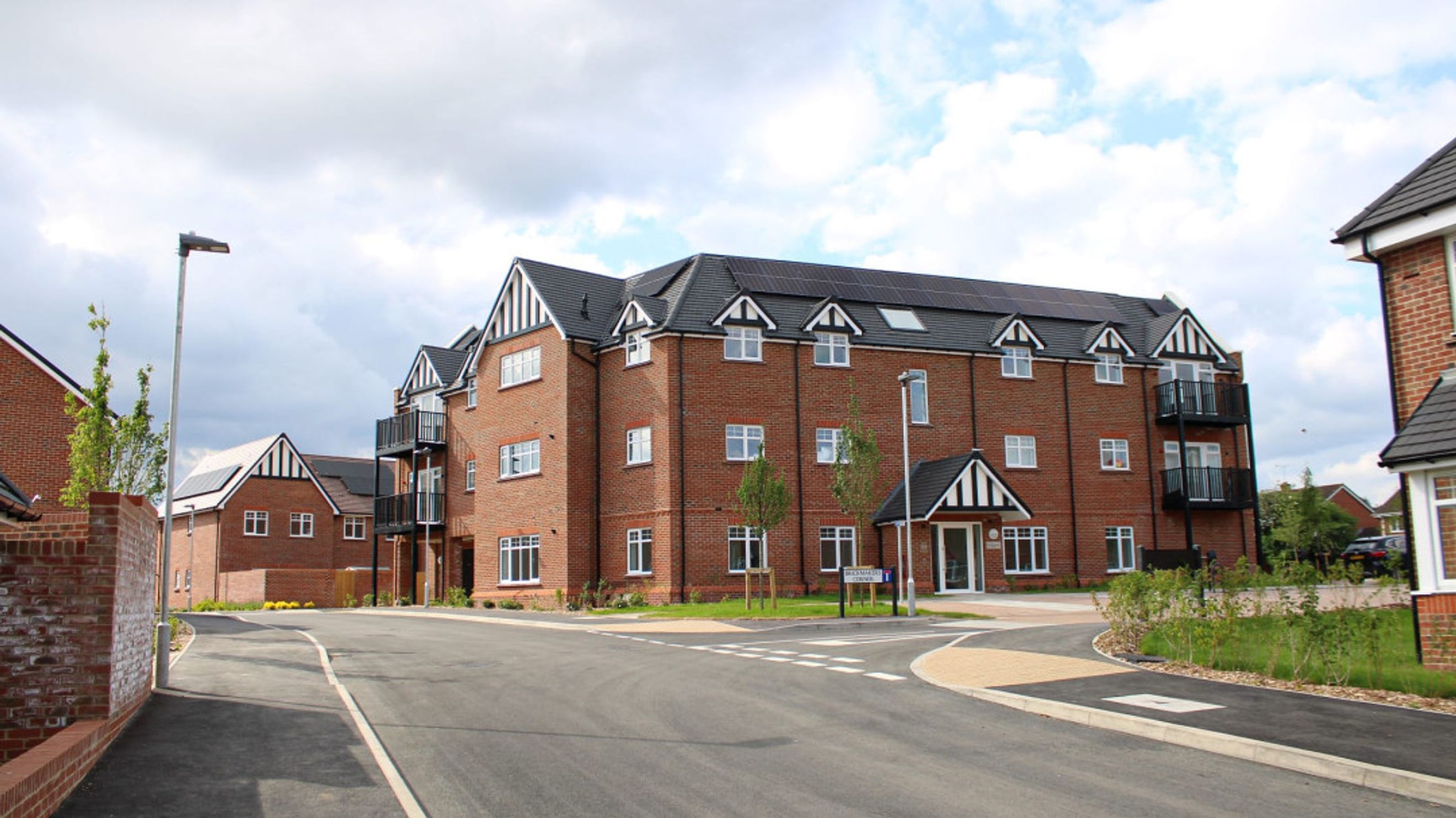 A street view of a modern brick apartment building with balconies and solar panels.