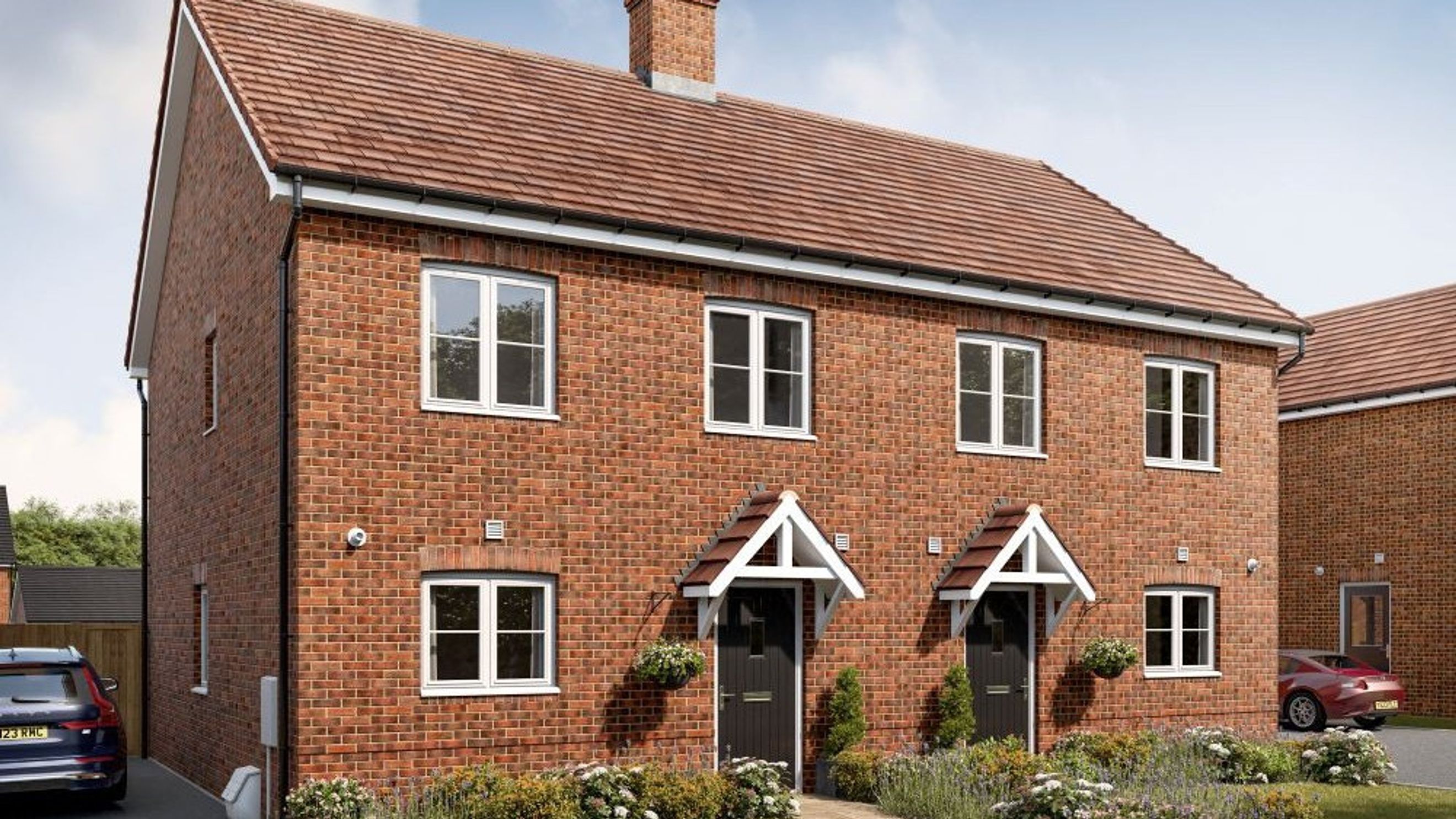 A pair of brick semi-detached houses with white-framed windows and pitched awnings over the front doors.