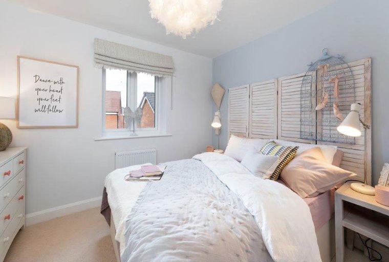 A bedroom with a bed, dresser, and a window.