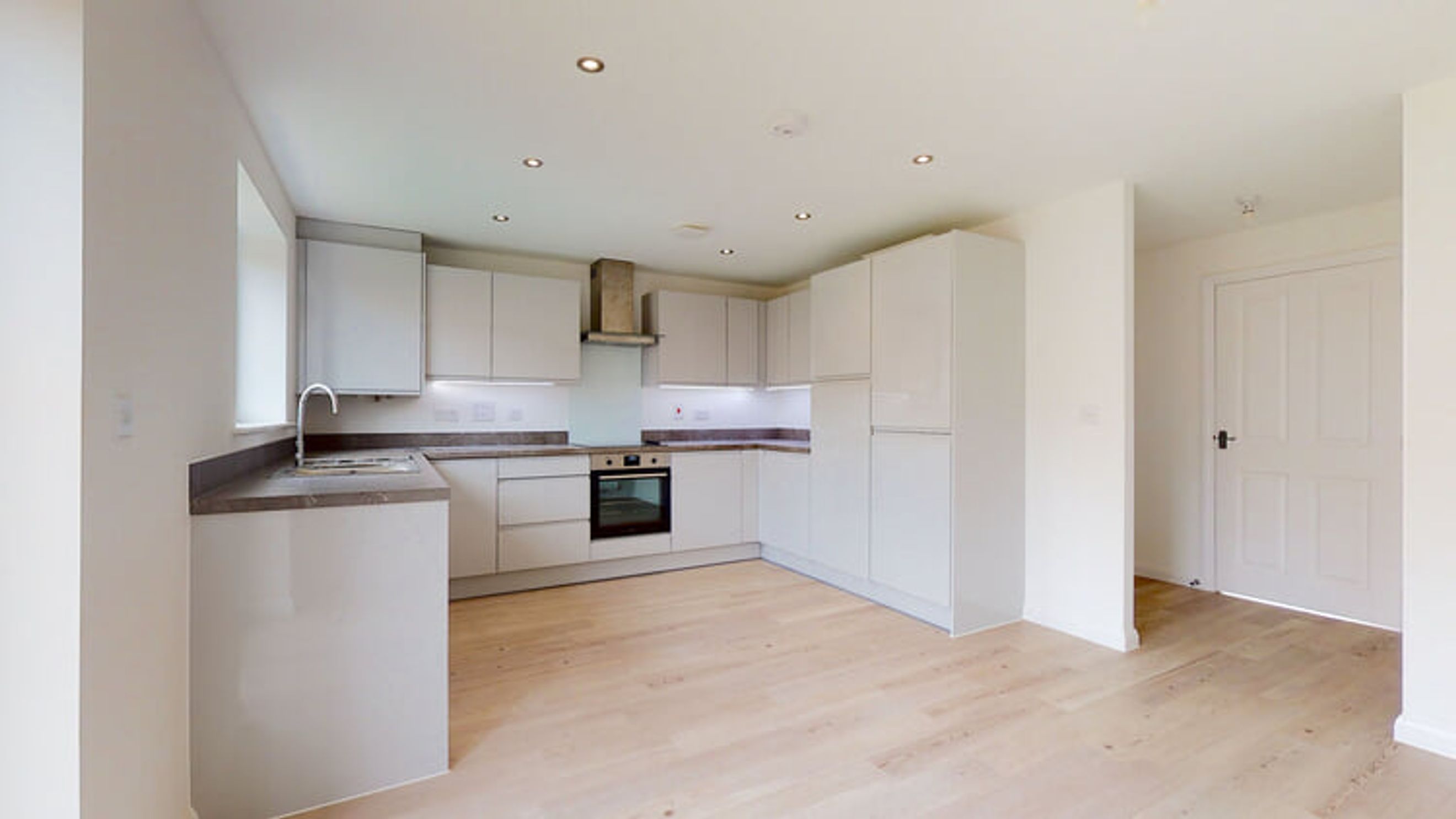 A modern kitchen with white cabinets, a sink, and an oven.