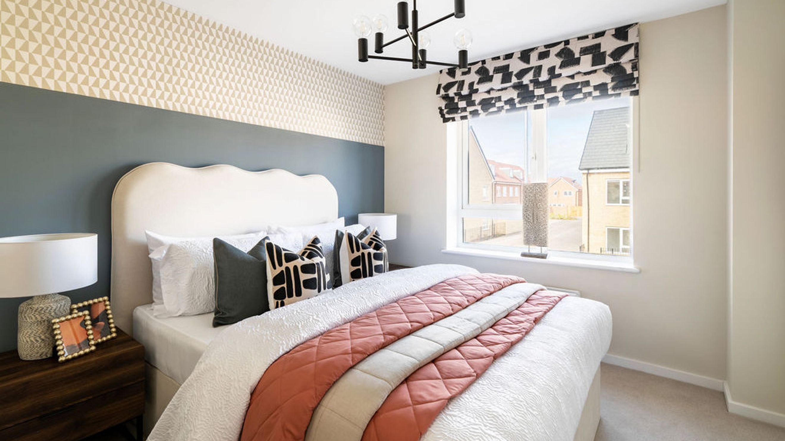 A bedroom with a bed, pillows, a nightstand, a lamp, and a window.