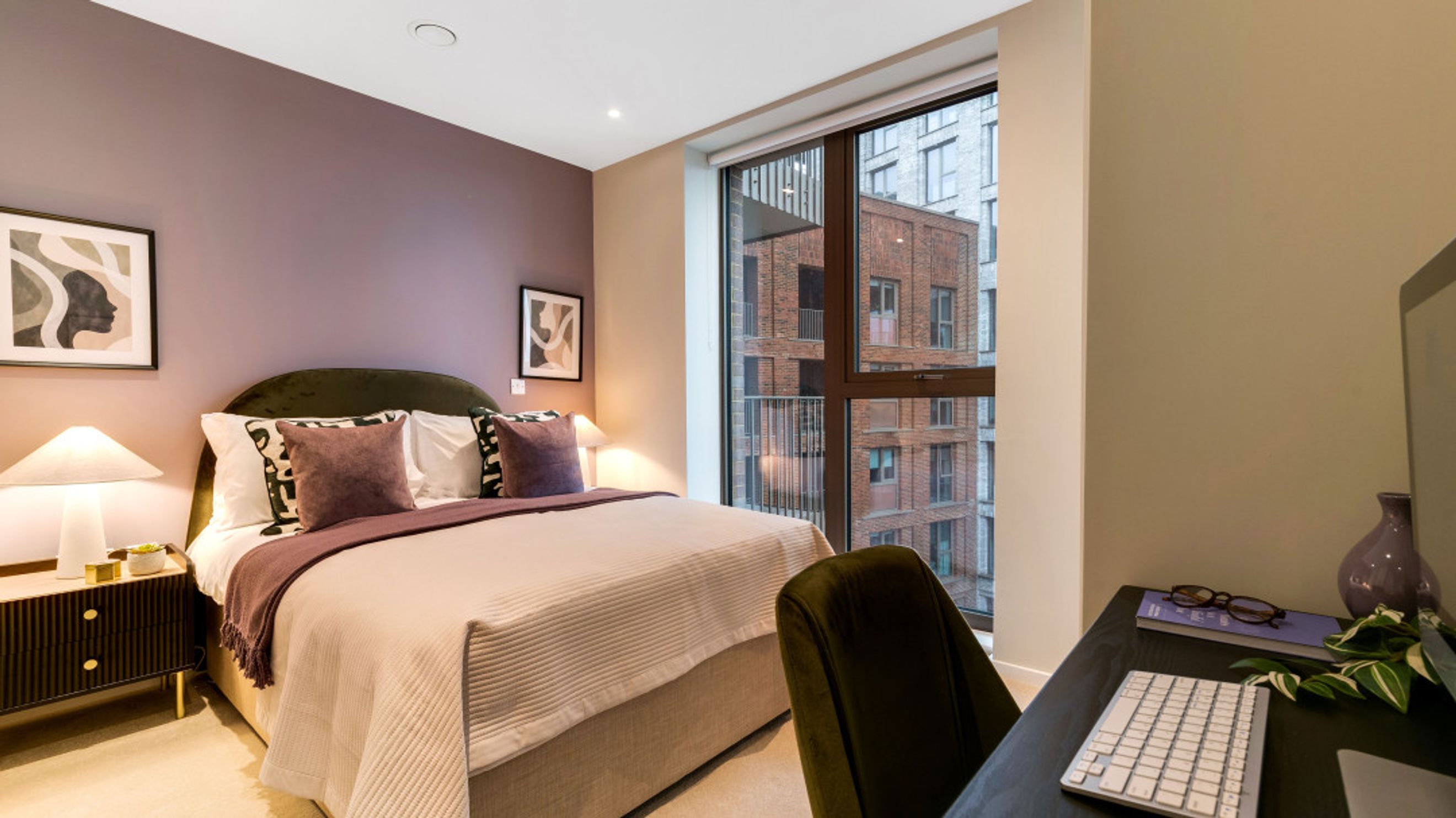 A bedroom with a bed, bedside table, and a desk with a computer.
