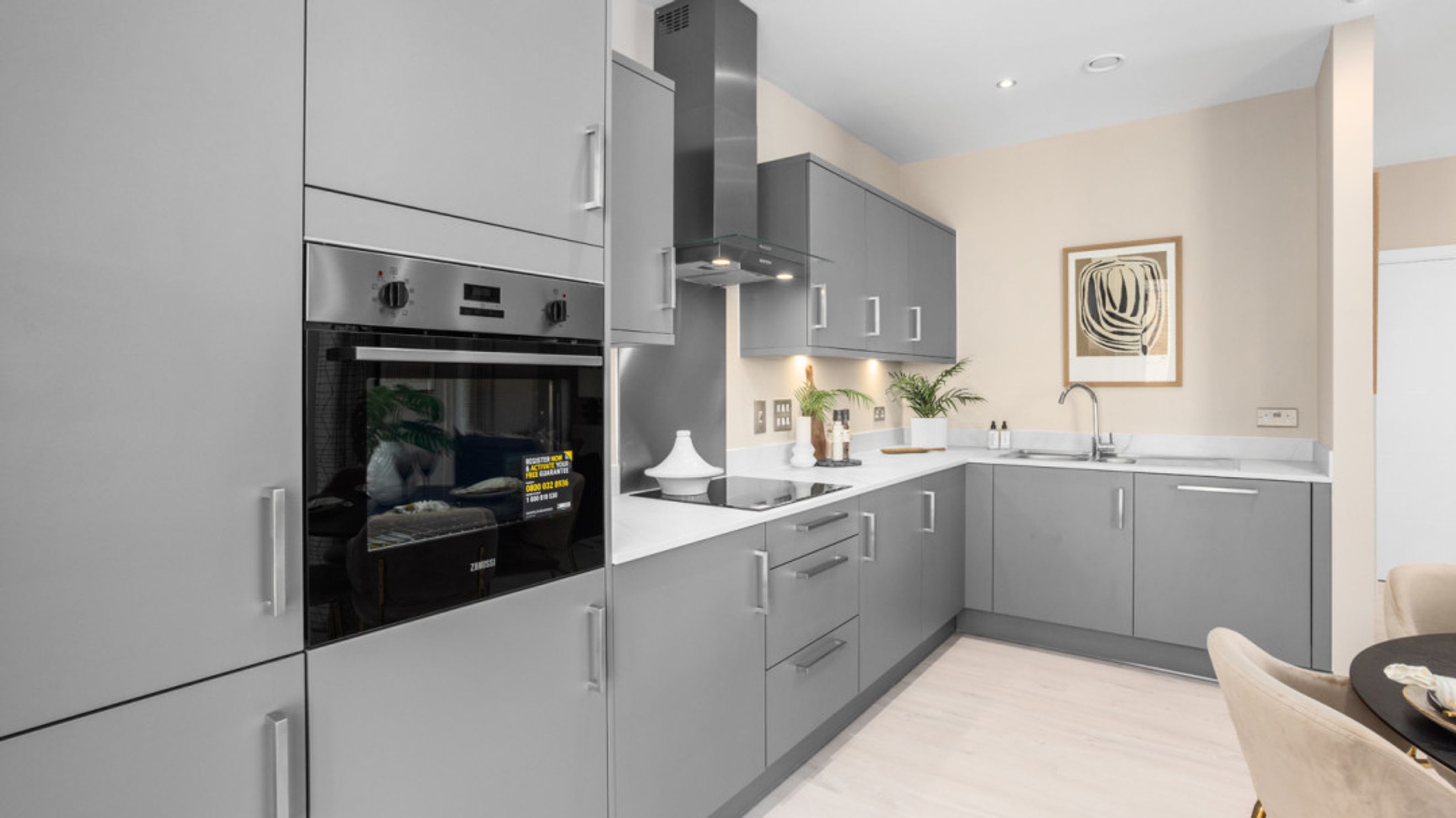 A modern kitchen with grey cabinets, a built-in oven, and a stovetop.