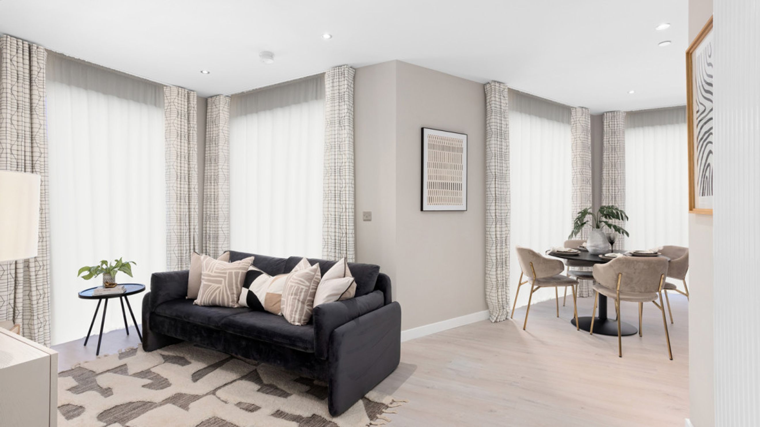 A living and dining area with a sofa, rug, and a dining table with chairs.