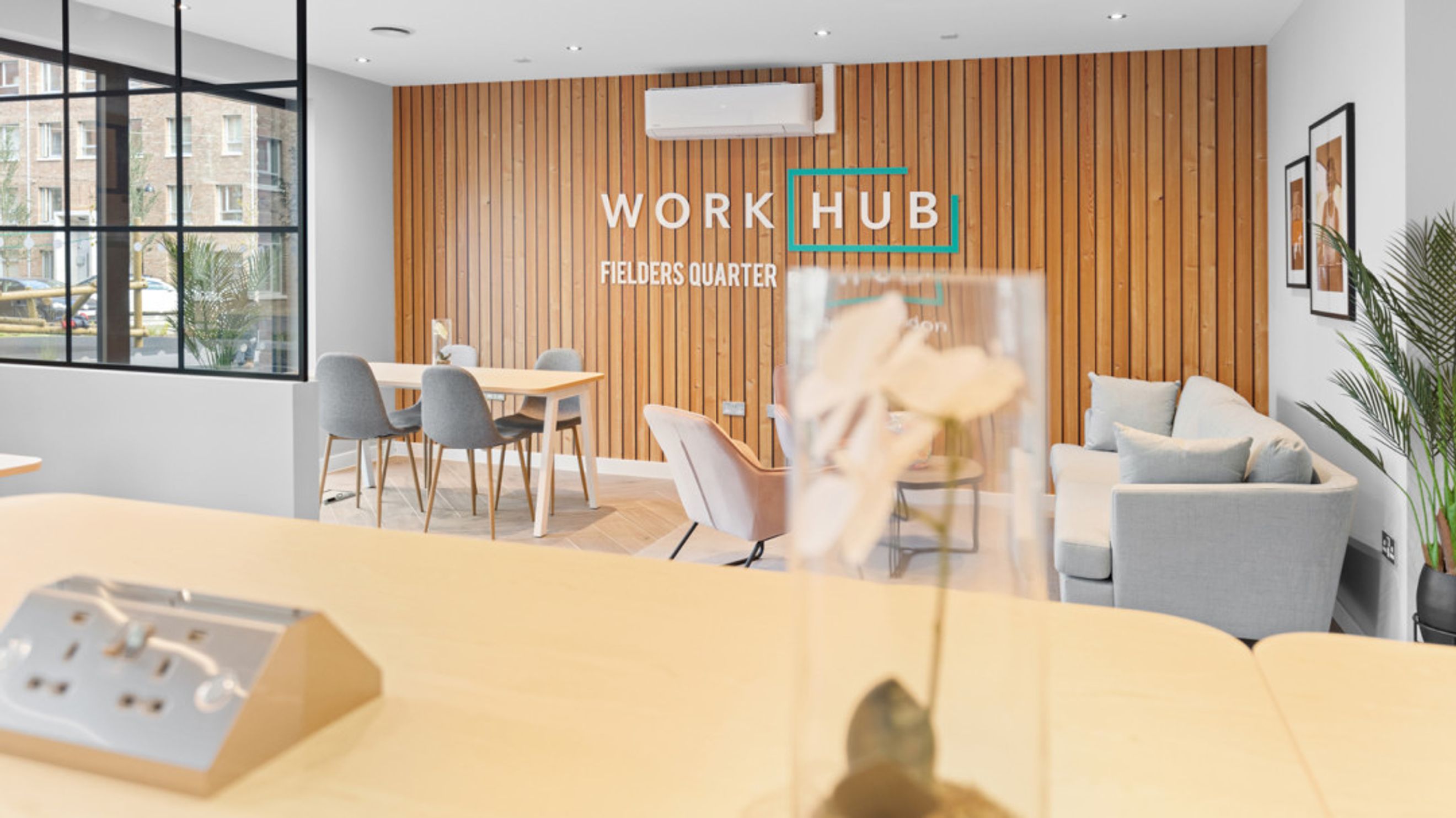 A co-working space with a wooden accent wall, seating areas, and a table with chairs.